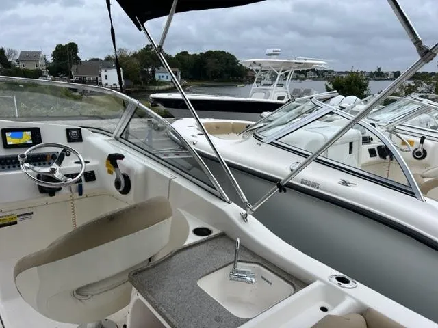 Slide: The Image of 2020 Key West 239 DFS boat interior with steering wheel and seating, docked near water. - 10