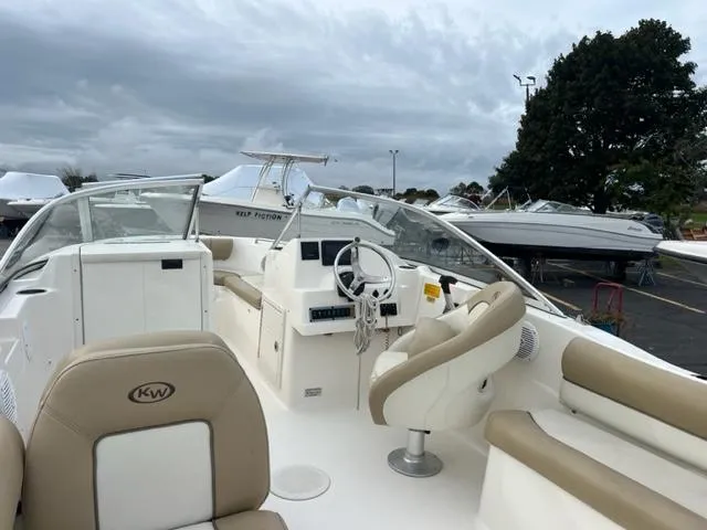 Slide: The Image of 2020 Key West 239 DFS boat interior with beige seating and steering wheel, parked outdoors. - 13