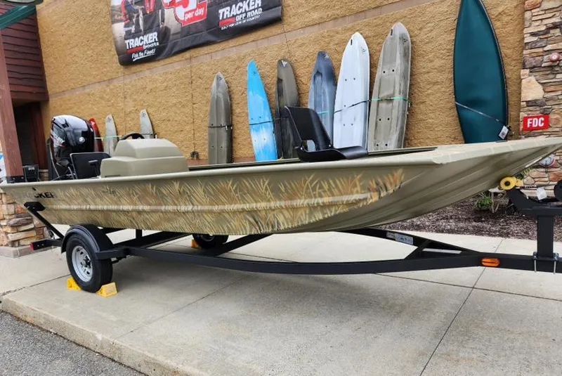 The Image of 2024 Tracker Grizzly 1648 SC boat on trailer, displayed outdoors with kayaks in the background. - 0