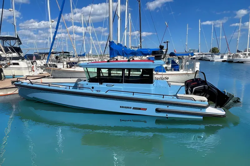 Slide: The Image of 2023 BRABUS Shadow 500 Cabin boat docked in a marina with sailboats. - 0