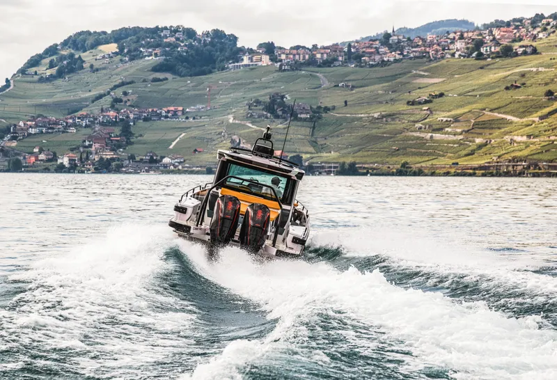 Slide: The Image of BRABUS Shadow 500 Cabin 2023 speeding on water with scenic hillside background. - 36