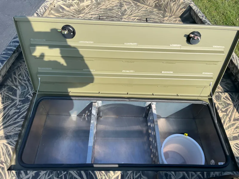 Slide: The Image of 2024 Lowe Outlet 20 boat storage compartment with open lid and bucket inside. - 13