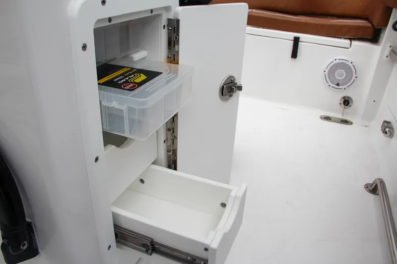 Slide: The Image of Storage compartment on the 2024 Sea Hunt Ultra 255 SE boat with drawers and a plastic container. - 28