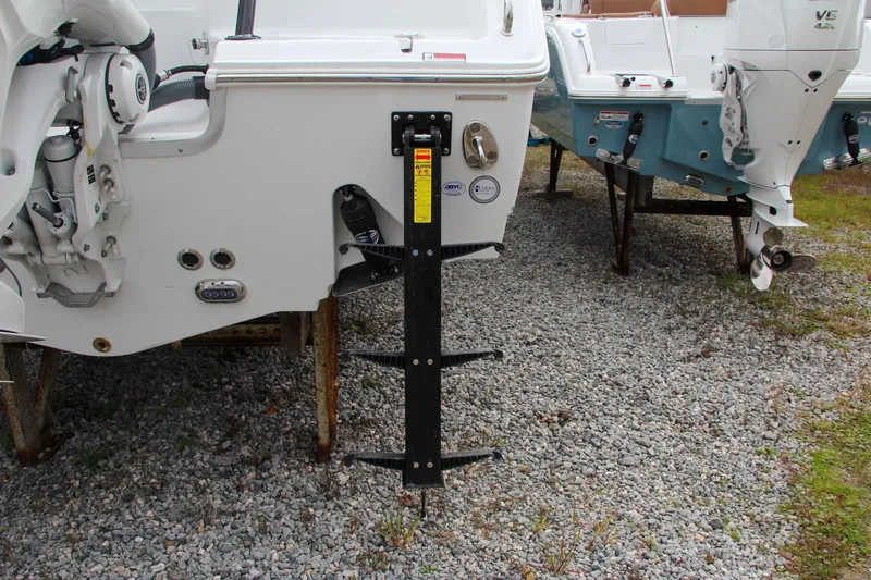 Slide: The Image of 2024 Sea Hunt Ultra 255 SE boat with a mounted ladder on gravel. - 9