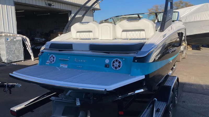 Slide: The Image of 2024 Regal LS4 Surf boat with white seating and blue accents on a trailer. - 1