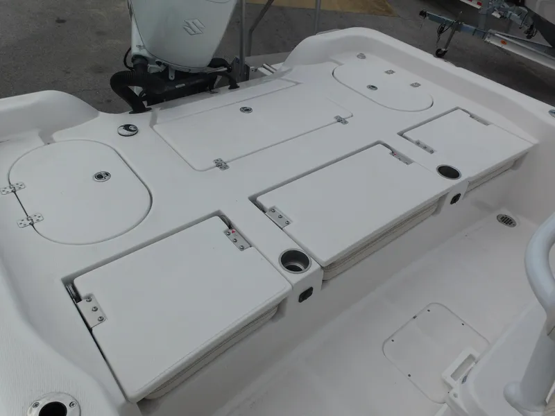 Slide: The Image of 2024 Blue Wave 2600 PureBay boat deck with storage compartments and Suzuki outboard motor. - 23