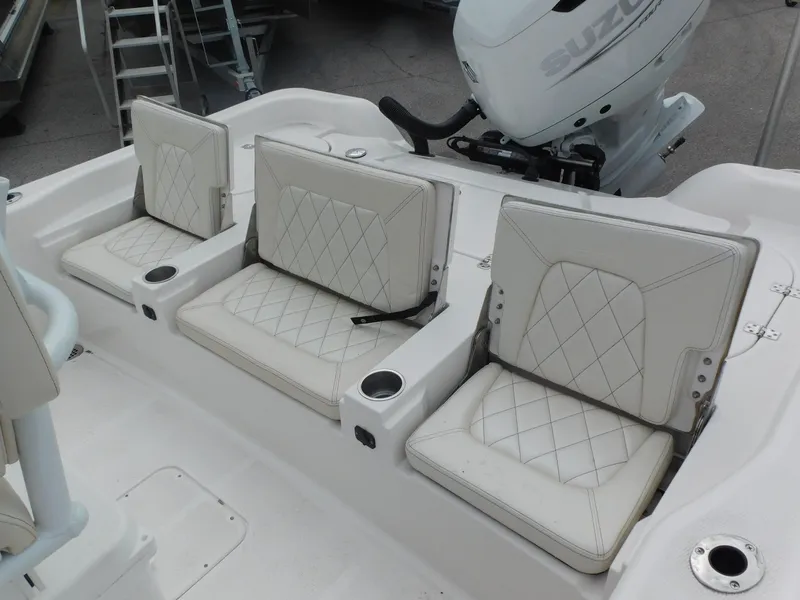 Slide: The Image of 2024 Blue Wave 2600 PureBay boat with white cushioned seating and Suzuki outboard motor. - 26