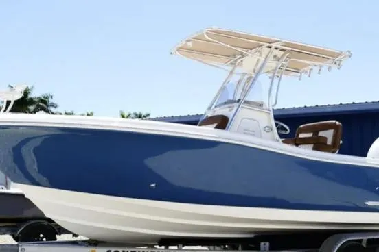 The Image of 2026 Pioneer 222 Islander boat with blue hull and T-top on trailer. - 0