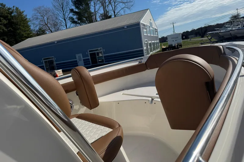 Slide: The Image of 2026 Pioneer 222 Islander boat interior with brown seating, near a blue building. - 7