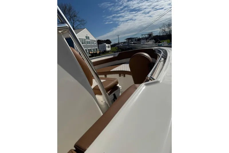 Slide: The Image of 2026 Pioneer 202 Sportfish boat with brown seating, parked outdoors under a blue sky. - 10