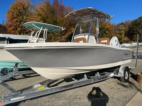 Slide: The Image of 2024 Pioneer 202 Sportfish boat with brown and white seating, docked outdoors. - 2