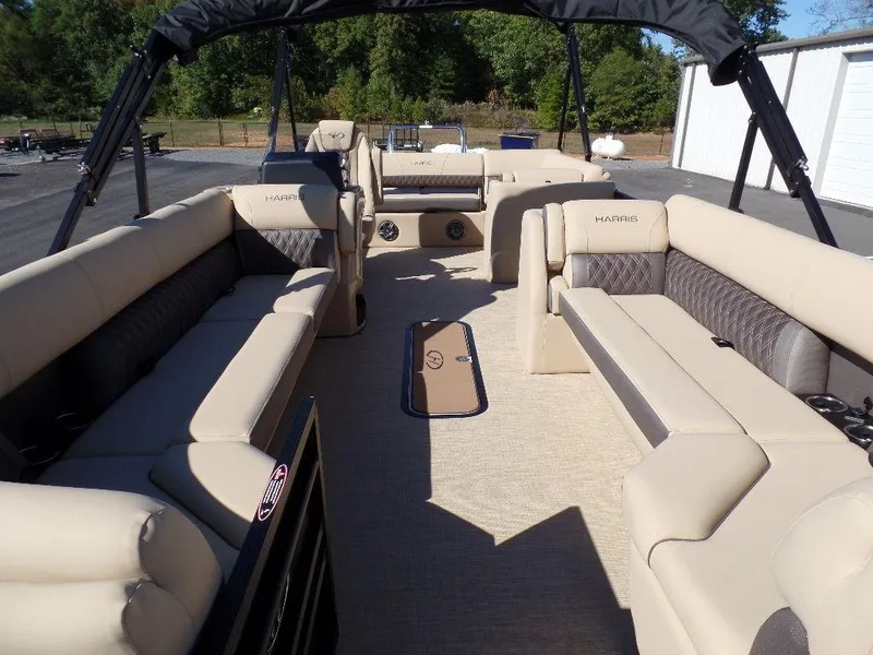 Slide: The Image of 2024 Harris Sunliner 250 pontoon boat with spacious beige seating and black canopy. - 4