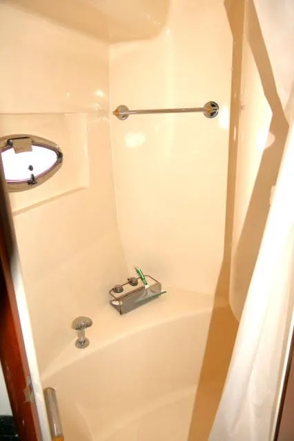 Slide: The Image of 2001 Carver 530 Voyager Pilothouse shower with porthole window and chrome fixtures. - 19