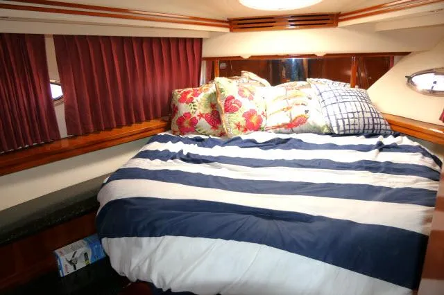 Slide: The Image of Luxurious bedroom in 2001 Carver 530 Voyager Pilothouse yacht with striped bedding and decorative pillows. - 23