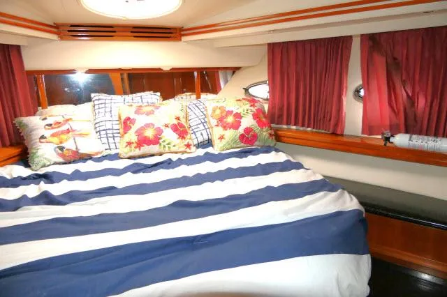 Slide: The Image of 2001 Carver 530 Voyager Pilothouse bedroom with striped bedding and floral pillows. - 24