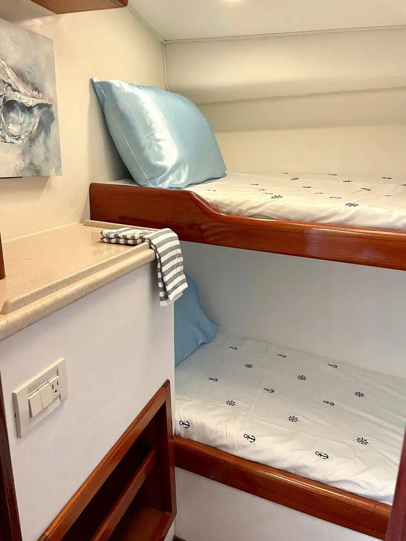 Slide: The Image of Bunk beds in the 2003 Cabo 45 Express cabin with blue pillows and striped towel. - 16