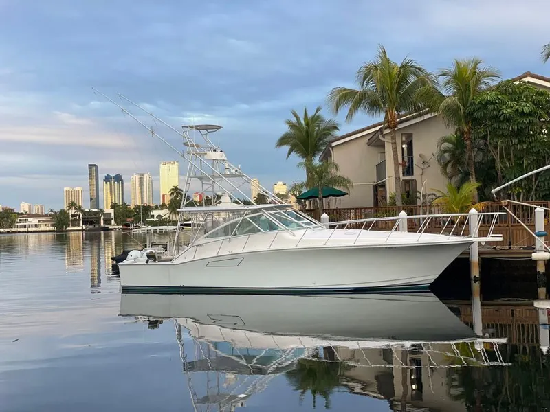 Slide: The Image of 2003 Cabo 45 Express yacht docked in a serene marina with cityscape background. - 20
