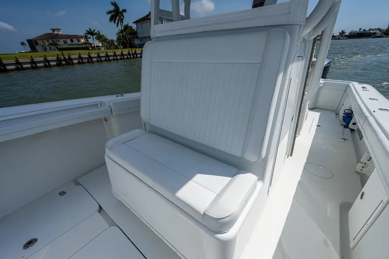 Slide: The Image of 2015 Yellowfin 32 boat interior with white seating, docked near waterfront homes. - 18