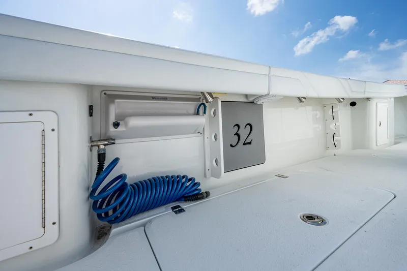Slide: The Image of 2015 Yellowfin 32 boat deck with storage compartments and coiled blue hose. - 26
