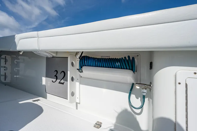 Slide: The Image of 2015 Yellowfin 32 boat interior with coiled blue hose and storage compartments. - 27