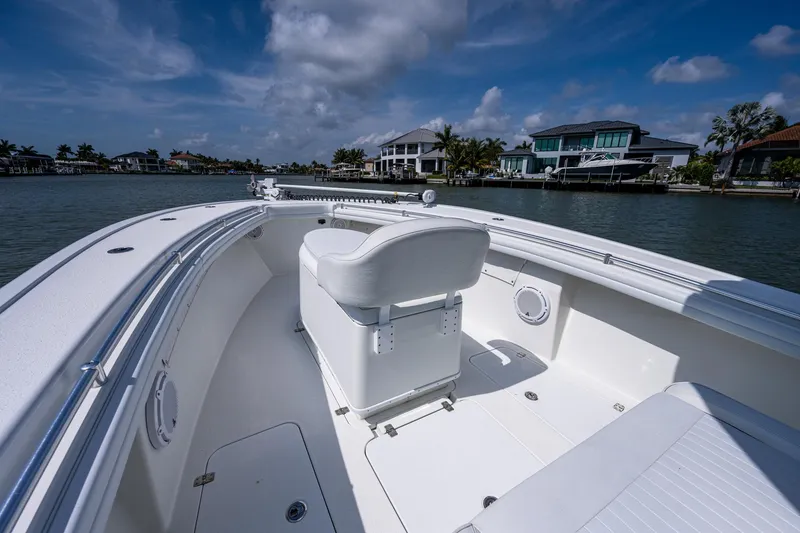 Slide: The Image of 2015 Yellowfin 32 boat on calm waters with modern waterfront homes in the background. - 8