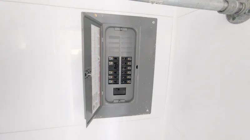 Slide: The Image of Electrical panel inside 2022 Houseboat 36' A&M Manufacturing, open with visible circuit breakers. - 16