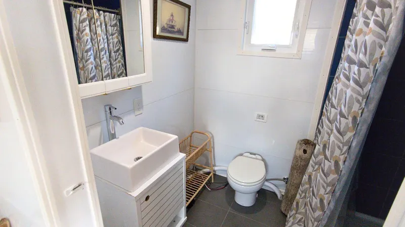 Slide: The Image of Modern houseboat bathroom with sink, toilet, and shower curtain, 2022 A&M Manufacturing model. - 9