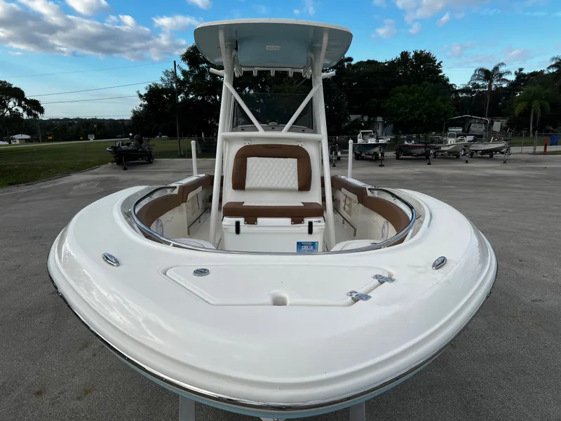 Slide: The Image of 2024 Pioneer 222 Sportfish boat with white and brown seating, docked outdoors. - 18