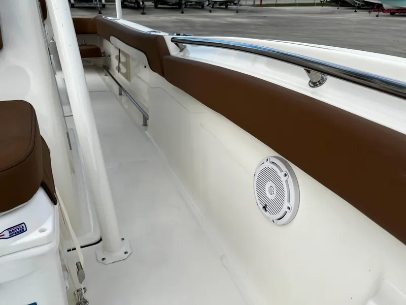 Slide: The Image of 2024 Pioneer 222 Sportfish boat interior with brown cushioned seating and built-in speaker. - 29