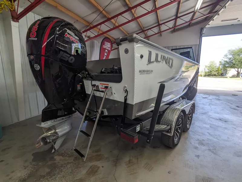 Slide: The Image of 2025 Lund 1875 Fisherman boat with a 150 HP outboard motor in a garage. - 2