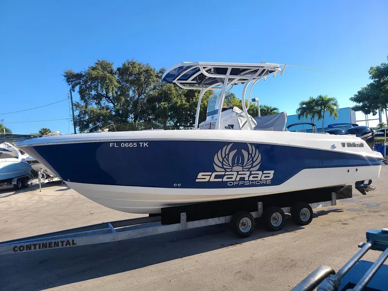 Slide: The Image of 2023 Wellcraft 242 Fisherman boat on trailer, blue and white, Scarab Offshore branding. - 4