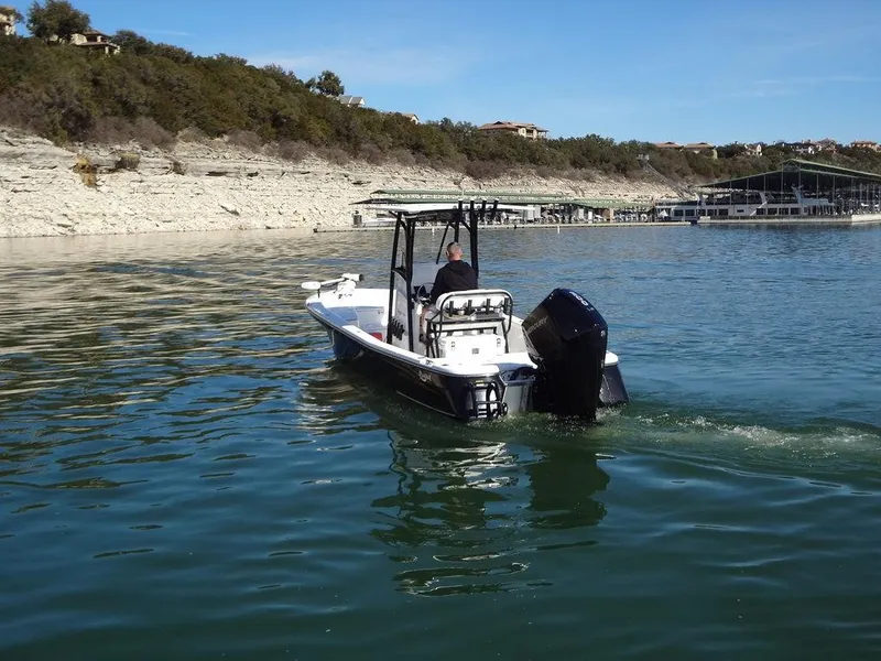 Slide: The Image of 2024 BlackJack 256 Bay boat cruising on a calm lake near rocky shoreline. - 10