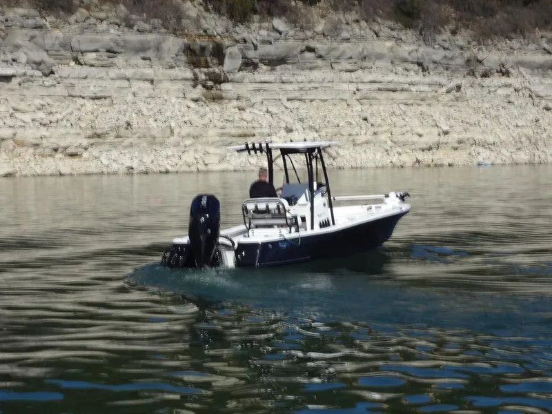 Slide: The Image of 2024 BlackJack 256 Bay boat cruising on a calm lake near rocky shoreline. - 3