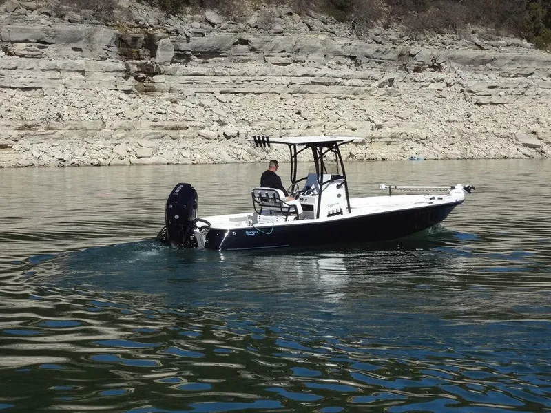 Slide: The Image of 2024 BlackJack 256 Bay boat on calm water near rocky shoreline. - 5
