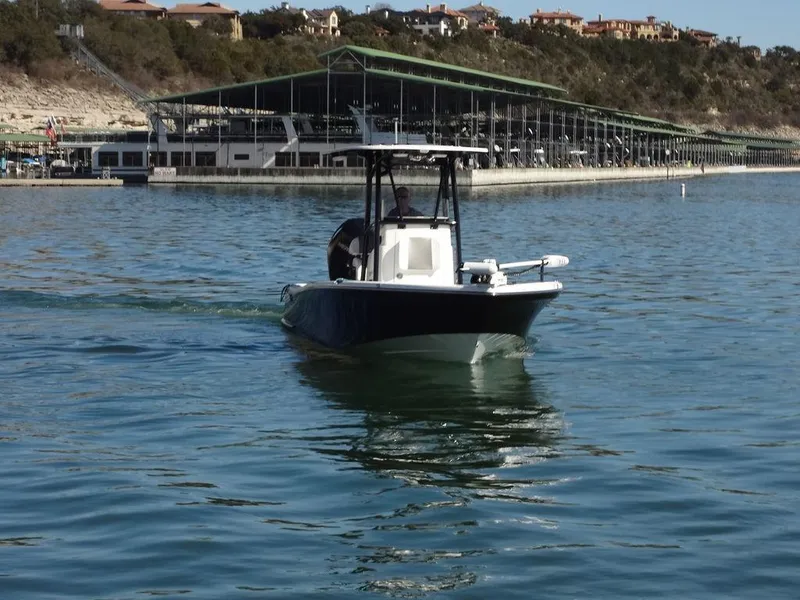 Slide: The Image of 2024 BlackJack 256 Bay boat cruising on a calm lake near a marina. - 8