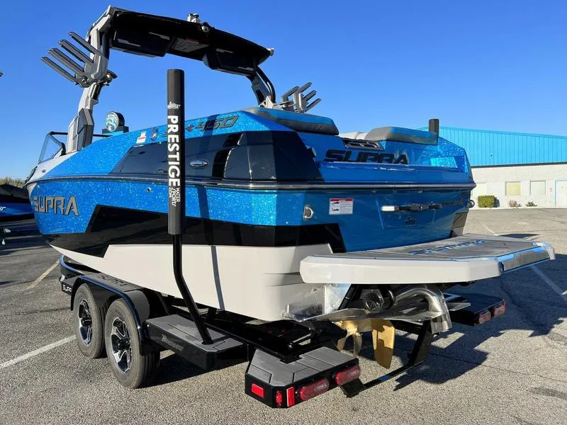 Slide: The Image of 2024 Supra SL boat on trailer, blue and black design, parked outdoors. - 22