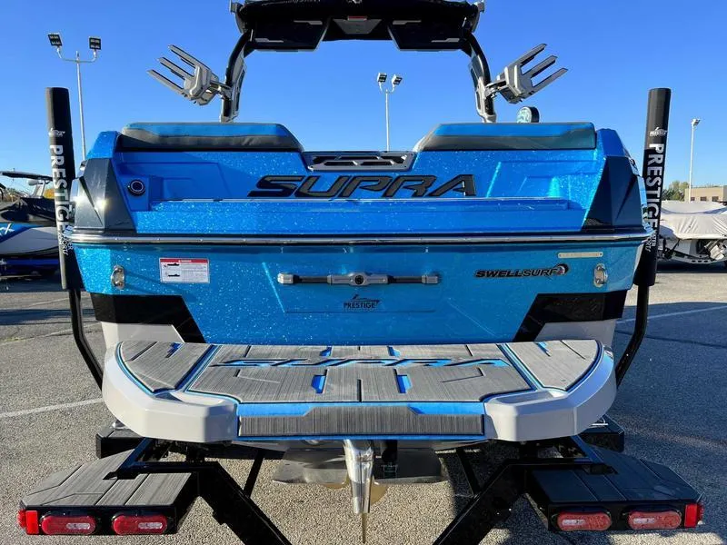Slide: The Image of 2024 Supra SL boat, blue exterior, rear view, parked on trailer. - 27