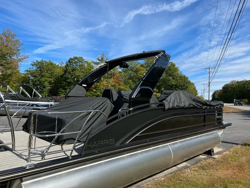 Slide: The Image of 2023 Harris Solstice DC 250 pontoon boat with black cover on a sunny day. - 4