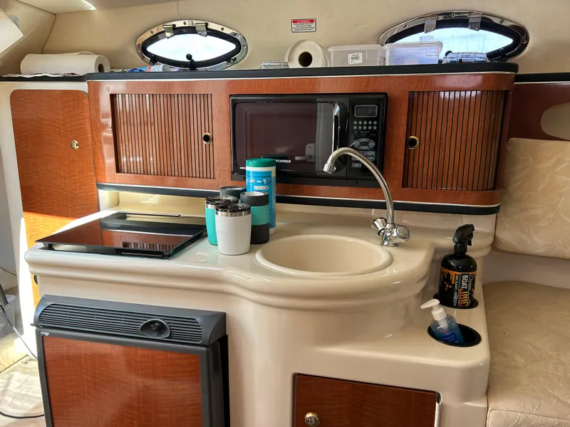 Slide: The Image of 2004 Sea Ray 260 DA boat galley with sink, microwave, and storage cabinets. - 9