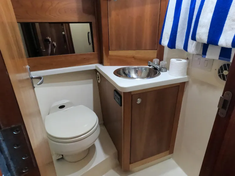 Slide: The Image of 2002 Luhrs 34 Convertible yacht bathroom with toilet, sink, and wooden cabinetry. - 28