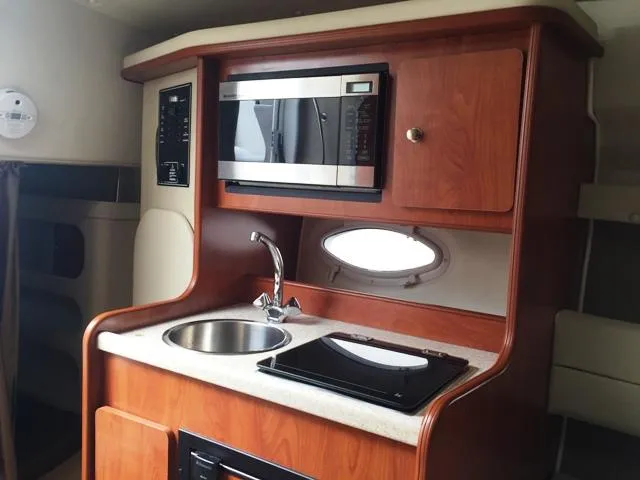 Slide: The Image of 2007 Rinker 270 Express Cruiser galley with microwave, sink, and stove. - 14