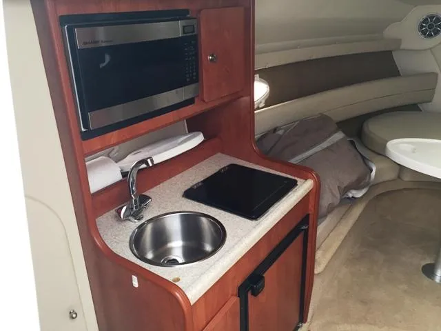 Slide: The Image of 2007 Rinker 270 Express Cruiser interior galley with sink, microwave, and seating area. - 16