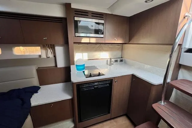 Slide: The Image of 2014 Sea Ray Sundancer 350 interior kitchen with modern appliances and wooden cabinetry. - 12