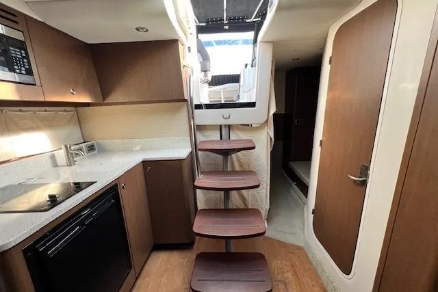 Slide: The Image of 2014 Sea Ray Sundancer 350 interior with modern kitchen and wooden stairs. - 17