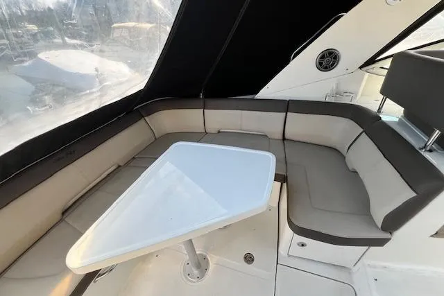Slide: The Image of 2014 Sea Ray Sundancer 350 interior with cushioned seating and a triangular table. - 28