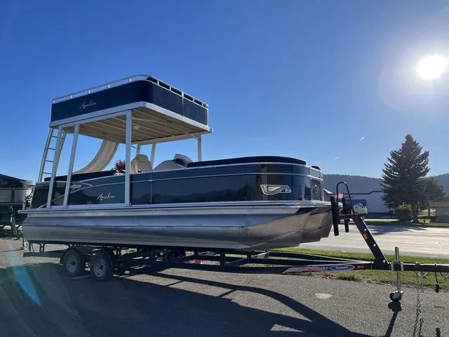 Slide: The Image of 2023 Avalon Catalina Entertainer Funship 25 FT pontoon boat on trailer under clear sky. - 2