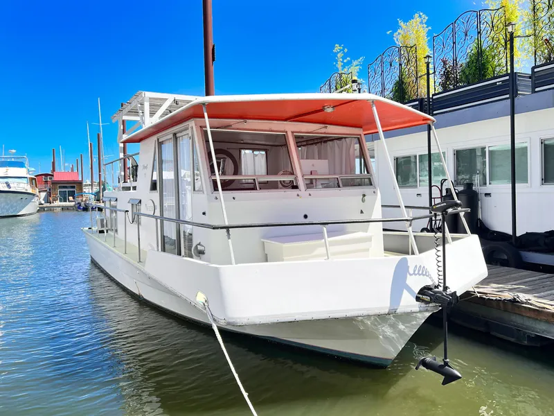 The Image of 1970 Tollycraft Tollyhome 36 houseboat docked in a marina under clear blue sky. - 0