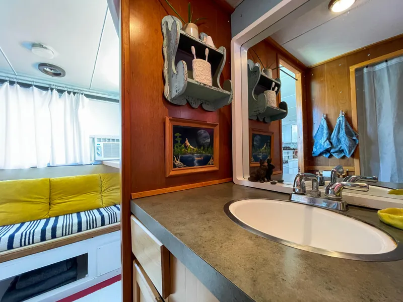 Slide: The Image of 1970 Tollycraft Tollyhome 36 interior with bathroom sink, mirror, and cozy seating area. - 11