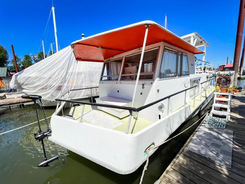 Slide: The Image of 1970 Tollycraft Tollyhome 36 boat docked, featuring a red canopy and spacious deck. - 12