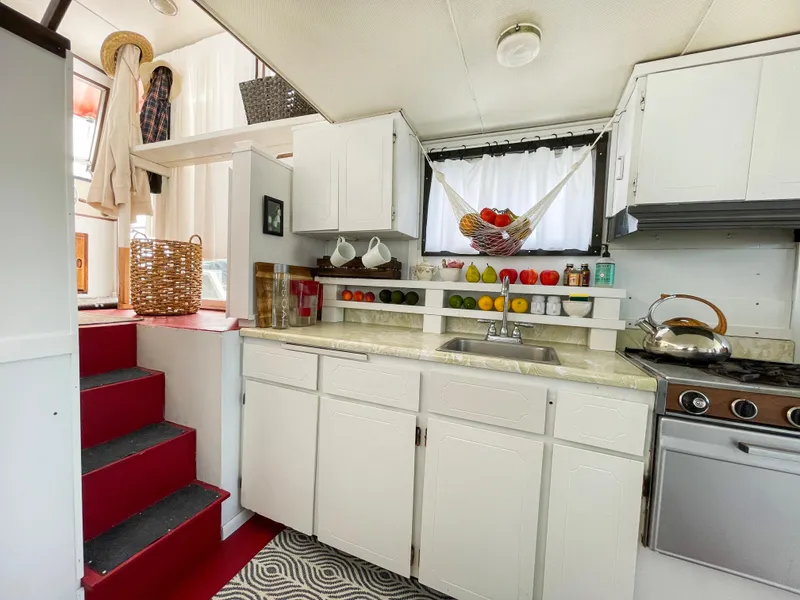 Slide: The Image of 1970 Tollycraft Tollyhome 36 kitchen with white cabinets, red stairs, and fruit basket. - 27